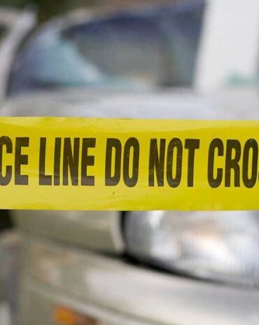 Yellow police tape in front of a car.