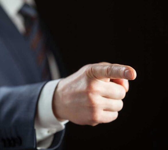 Person pointing with finger, wearing a suit.