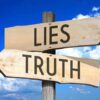 Signs pointing to Lies and Truth against sky.
