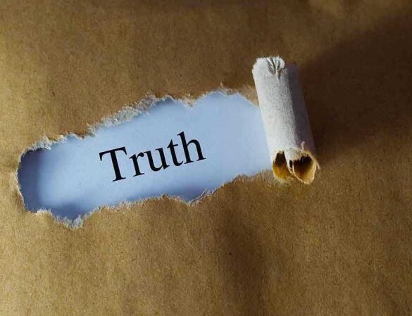 Ripped paper reveals word truth underneath brown surface