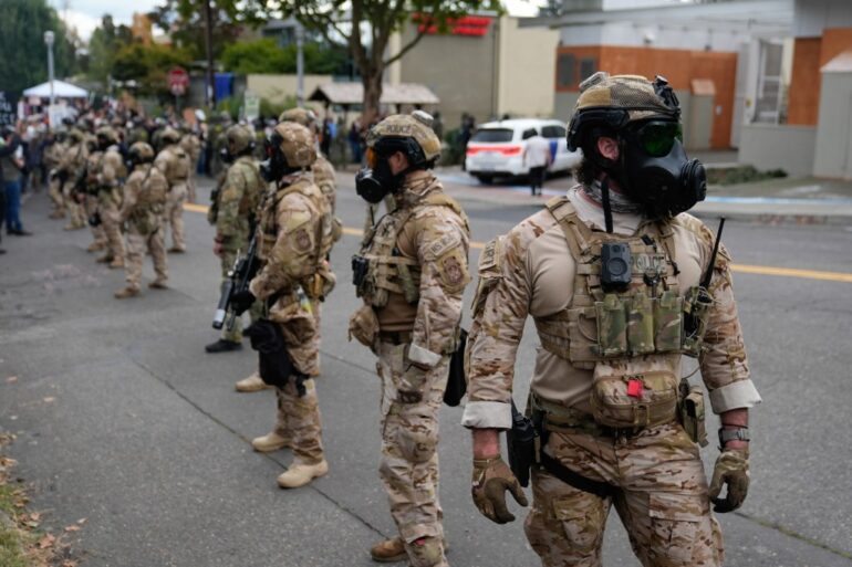 Law enforcement officers block the road for a vehicle to enter a U.S. Immigration and Customs Enforcement facility on Saturday, Oct. 4, 2025, in Portland, Ore.