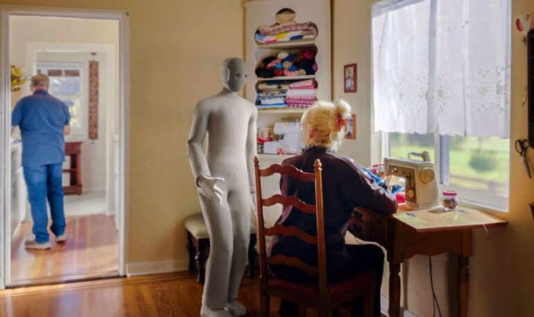 NEO humanoid robot assisting an elderly woman sewing while a man stands in the background.