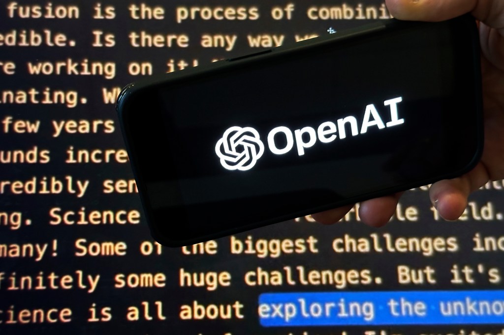 A hand holds a phone displaying the OpenAI logo over a screen showing text.