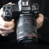 A person holding a Canon EOS R5 mirrorless camera with a Canon RF 35mm f/1.4 L VCM Lens