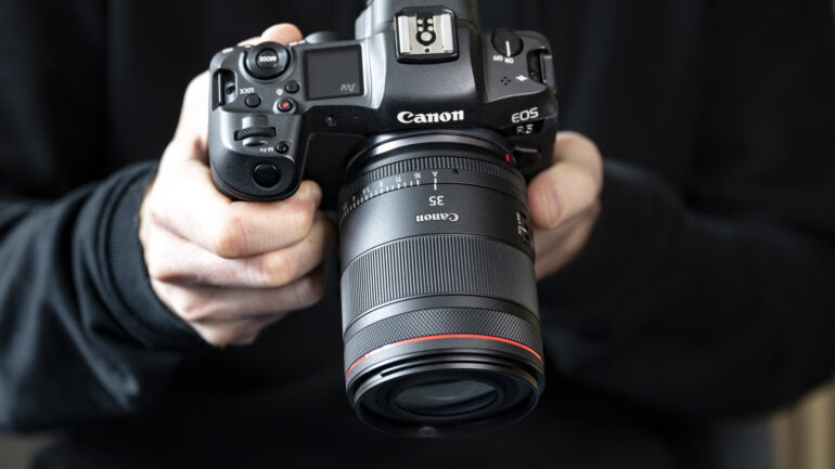 A person holding a Canon EOS R5 mirrorless camera with a Canon RF 35mm f/1.4 L VCM Lens