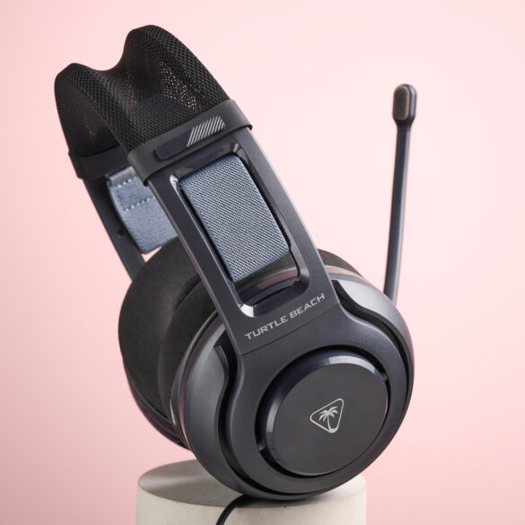 The Turtle Beach Atlas 200 sat on top of a cylinder, with the mic folded up, in front of a pink background.