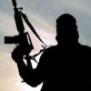 Silhouette of a person holding a rifle against a cloudy sky