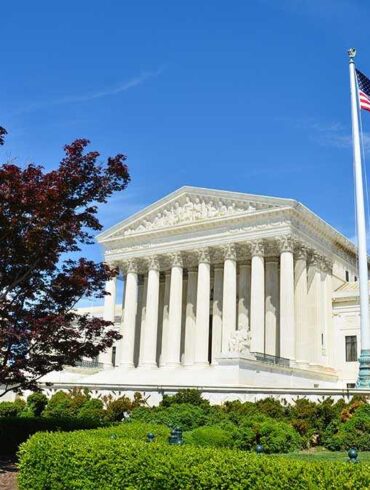 Supreme Court building with American flag and surrounding greenery