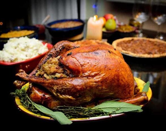 A beautifully roasted turkey on a festive table surrounded by side dishes and decorations