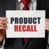 Product Recall sign held by person in suit.