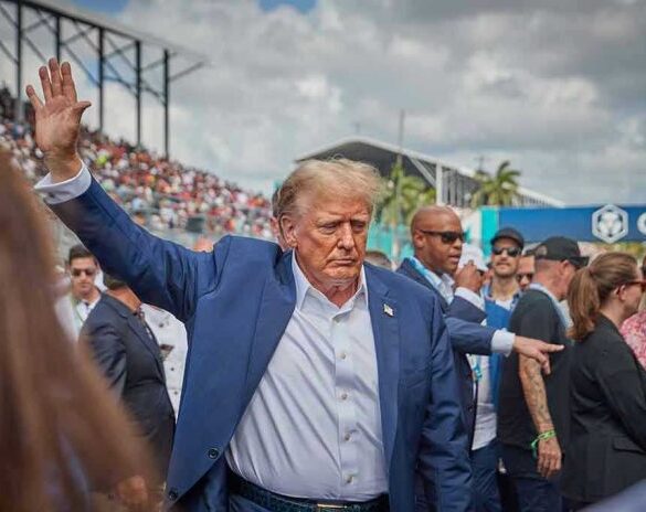 Person in blue suit waving at outdoor event.