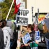 Protesters hold signs against Immigration and Customs Enforcement during the "ICE and DHS Out of Little Village" demonstration at the predominantly Mexican-American neighborhood of Little Village, also known as "La Villita", in Chicago, Illinois on October 25, 2025. US President Donald Trump's administration has asked the Supreme Court to lift lower court rulings blocking his deployment of the National Guard in Chicago. Trump has ordered hundreds of National Guard troops to Chicago, claiming they are needed to combat crime and to protect immigration agents and facilities in America's third-largest city. (Photo by KAMIL KRZACZYNSKI / AFP) (Photo by KAMIL KRZACZYNSKI/AFP via Getty Images)