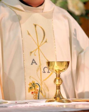 A priest holding a golden chalice during a religious ceremony