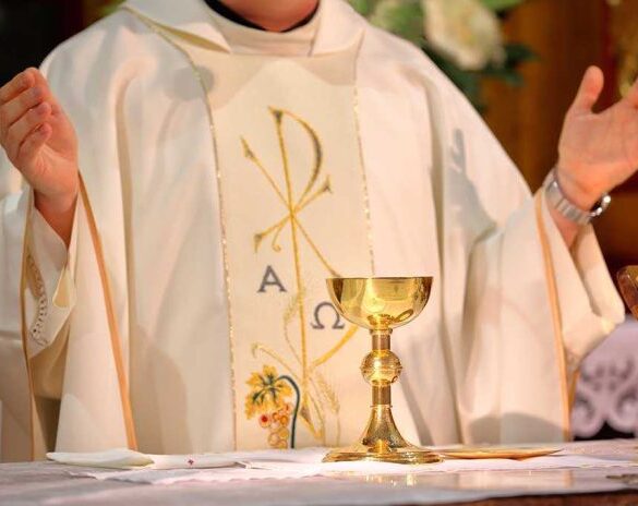 A priest holding a golden chalice during a religious ceremony