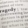 Close-up of the word 'Tragedy' in a dictionary with its definition