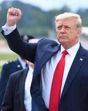 Man in suit raising fist near parked car.