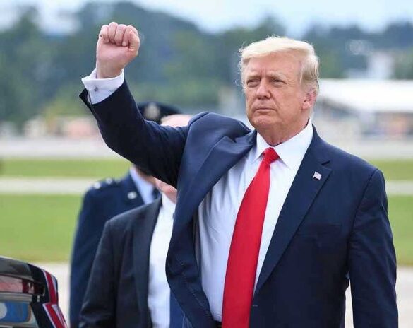 Man in suit raising fist near parked car.