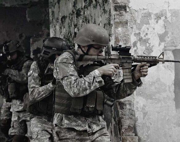 Soldiers in tactical gear advancing through a damaged building