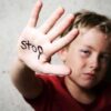 A child holding up a hand with the word stop written on it