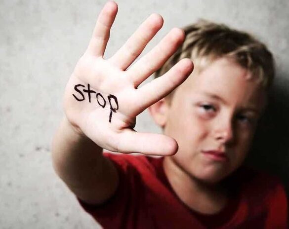 A child holding up a hand with the word stop written on it
