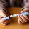 Hands holding an Ozempic injection pen.