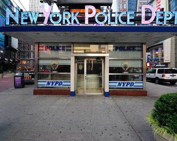 NYPD precinct building with signs on a city street