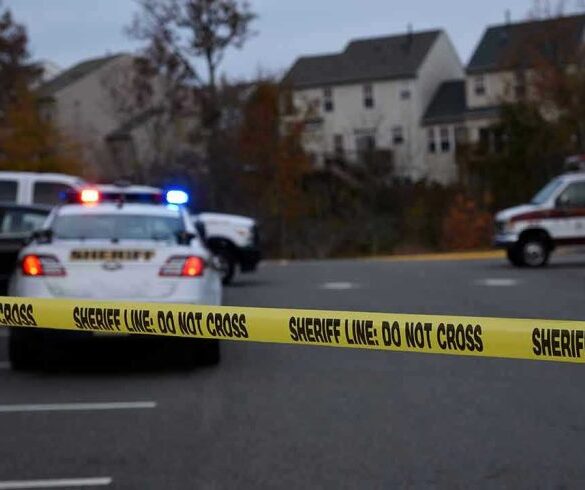 Sheriff line tape blocking scene with police and ambulance.