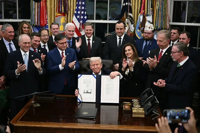 US President Donald Trump (C) shows the signed bill package to re-open the federal government in the Oval Office of the White House in Washington, DC, on November 12, 2025. Congress on Wednesday ended the longest government shutdown in US history, 43 days that paralyzed Washington and left hundreds of thousands of workers unpaid while Republicans and Democrats played a high-stakes blame game. The Republican-led House of Representatives voted largely along party lines to approve a Senate-passed package that will reopen federal departments and agencies, as many Democrats fume over what they see as a capitulation by party leaders. (Photo by Brendan SMIALOWSKI / AFP) (Photo by BRENDAN SMIALOWSKI/AFP via Getty Images)