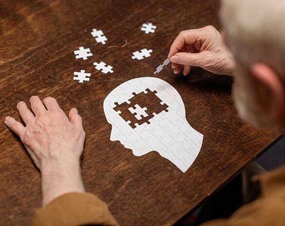 Elderly person completing head-shaped jigsaw puzzle.