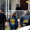 Members of the FBI Joint Terrorism Task Force stand in the front yard as they search a home in Dearborn, Michigan, on October 31, 2025. FBI Director Kash Patel said Friday that the agency had thwarted a "potential terrorist attack" planned in the northern state of Michigan over Halloween weekend. Patel said the FBI arrested multiple subjects. (Photo by JEFF KOWALSKY / AFP) (Photo by JEFF KOWALSKY/AFP via Getty Images)