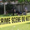 Yellow crime scene tape blocking grassy area.