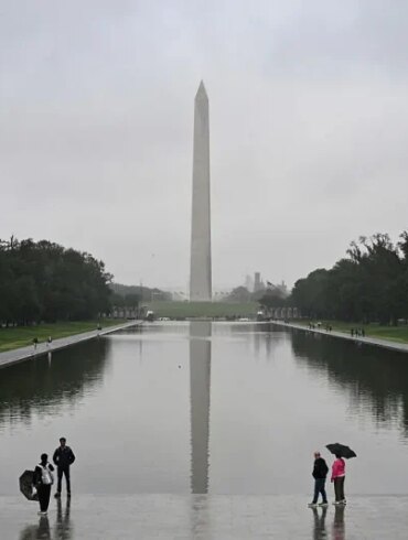 People stand near the Lincoln Memorial Reflecting Pool after a rainstorm in Washington DC, on May 28, 2025. (Photo by ALEX WROBLEWSKI / AFP) (Photo by ALEX WROBLEWSKI/AFP via Getty Images)