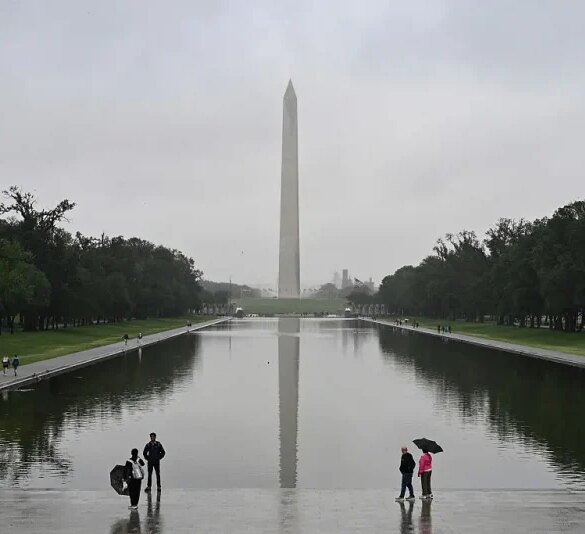 People stand near the Lincoln Memorial Reflecting Pool after a rainstorm in Washington DC, on May 28, 2025. (Photo by ALEX WROBLEWSKI / AFP) (Photo by ALEX WROBLEWSKI/AFP via Getty Images)