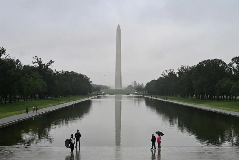 People stand near the Lincoln Memorial Reflecting Pool after a rainstorm in Washington DC, on May 28, 2025. (Photo by ALEX WROBLEWSKI / AFP) (Photo by ALEX WROBLEWSKI/AFP via Getty Images)