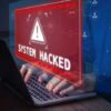 Warning sign System Hacked on laptop screen.