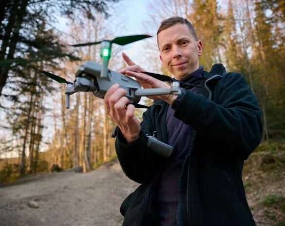 Person holding a drone in a forest.