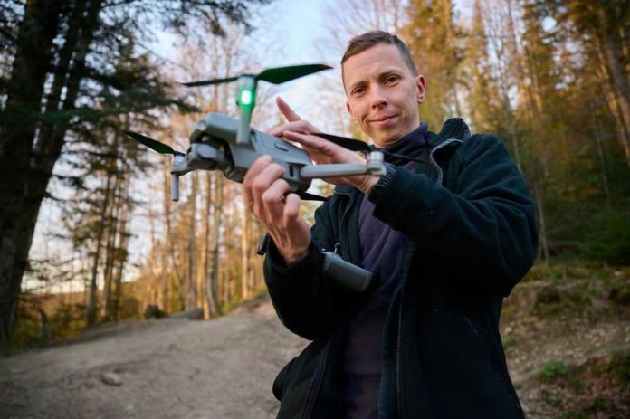 Person holding a drone in a forest.