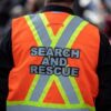 Person wearing a bright orange search and rescue vest