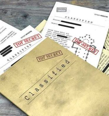 Classified documents with Top Secret stamps on wooden surface.