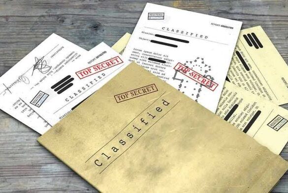 Classified documents with Top Secret stamps on wooden surface.
