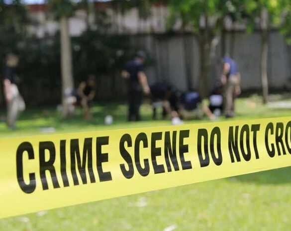 Yellow crime scene tape blocking grassy area.