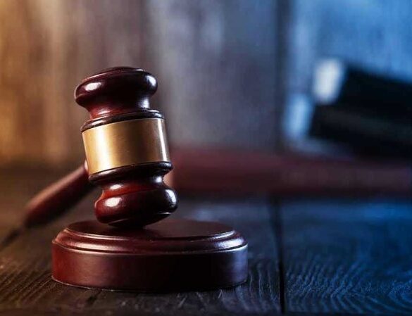 Gavel on wooden table in dimly lit room.