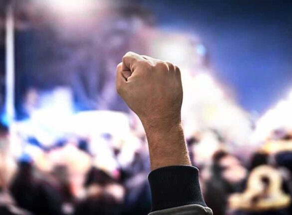 Raised fist in a crowd at night.