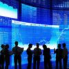 Silhouetted business professionals in front of digital stock market displays