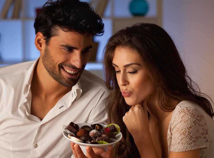 A couple sharing a plate of desserts in a cozy indoor setting