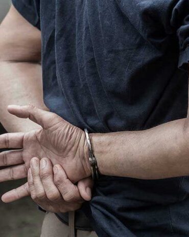 Person in handcuffs with hands behind back.