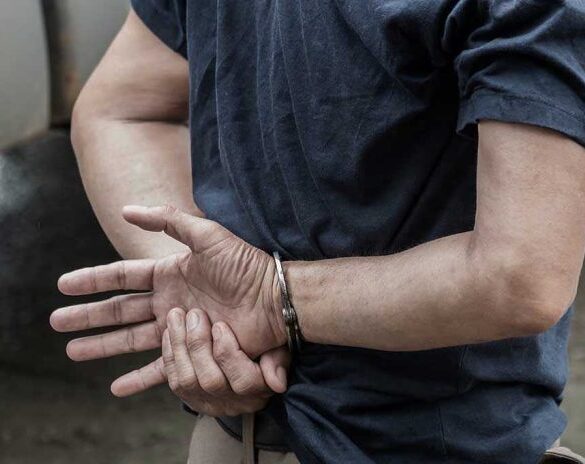 Person in handcuffs with hands behind back.