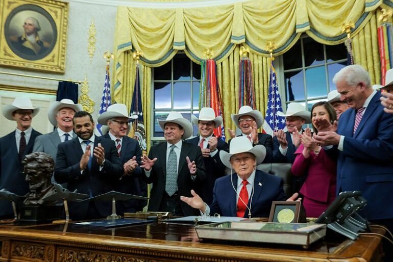 WASHINGTON, DC - DECEMBER 12: U.S. President Donald Trump puts on a hat given to him by the 1980 U.S. Olympic men’s ice hockey team as Trump honors the team in the Oval Office of the White House on December 13, 2025 in Washington, DC. Trump honored the ‘Miracle on Ice’ team, who defeated the Soviet Union and went on to win the 1980 Gold medal in Ice Hockey, by signing a bill to award the players congressional gold medals. (Photo by Anna Moneymaker/Getty Images)