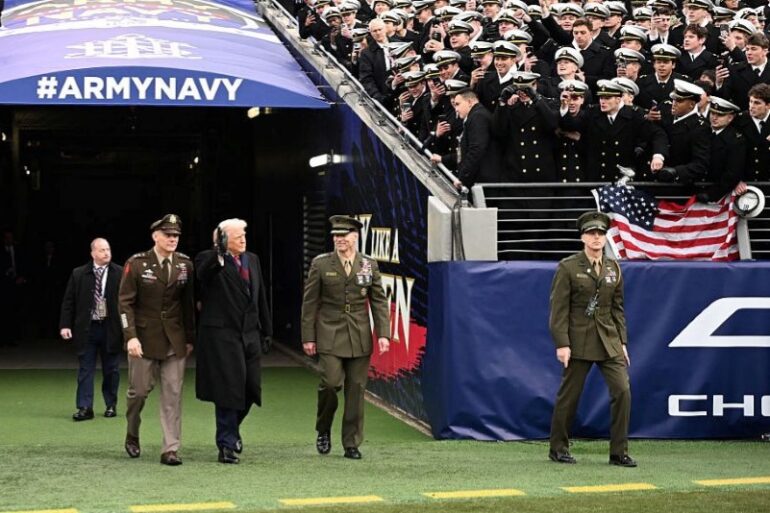 US President Donald Trump waves as he arrives on the field before the college football game between the US Army and Navy at the M&T Bank Stadium in Baltimore, Maryland, on December 13, 2025. (Photo by Alex WROBLEWSKI / AFP via Getty Images)