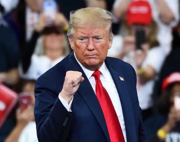 Man in suit making a fist gesture at rally.